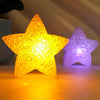 A bright yellow LED star light next to a purple star light on a surface.