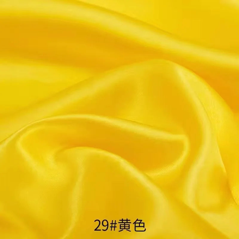 Yellow satin fabric draped and folded for sewing or DIY projects
