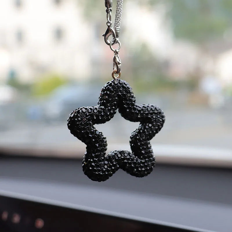 A black rhinestone star charm with crystal accents hanging from a silver chain.