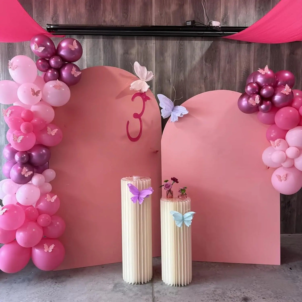A pink and white balloon party decoration set featuring balloons, pink arches, and decorative elements.