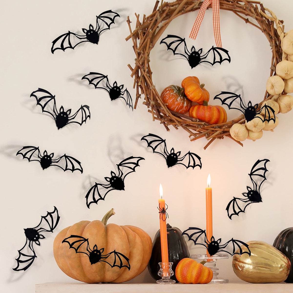 A set of twelve black bat wall decals attached to a natural twig wreath and pumpkins.