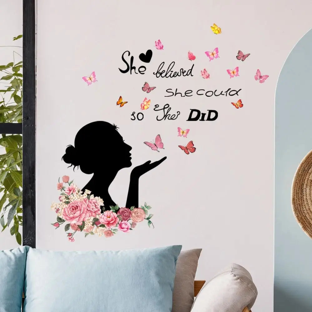 A wall decal featuring a silhouette of a woman, butterflies, and pink and peach flowers on a white wall.