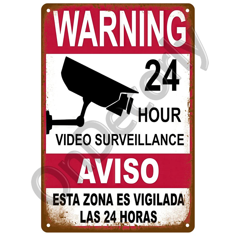 Vintage metal sign warning about 24-hour video surveillance in Spanish and English.