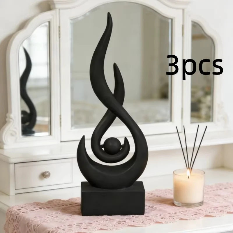 A black, three-pronged flame sculpture decor sits on a dark base in front of a white framed mirror.