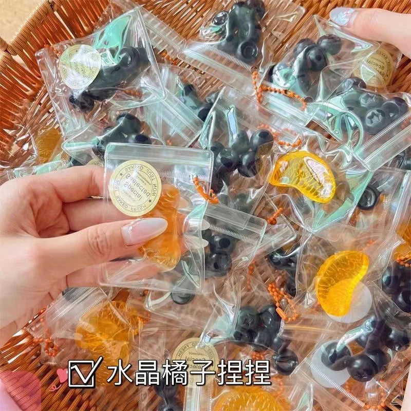 Handmade fruit keychains in various colors like orange and black are packaged in clear plastic bags