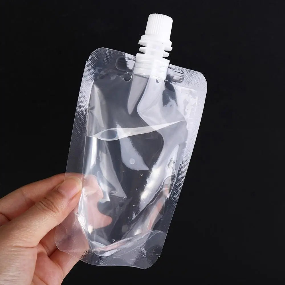 A hand holds a clear, squeezable liquid drink pouch with a white cap against a black background.