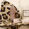 A leopard print storage rack displaying amethyst and quartz crystals with gold chains.