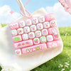 A pink and white cartoon animal keyboard keycap fidget toy is shown inside a white fabric bag outdoors.