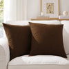 Two dark brown linen pillows resting on a white sofa with a framed picture in the background.