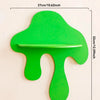 A bright green, cherry-shaped wooden wall shelf with a horizontal groove for display.