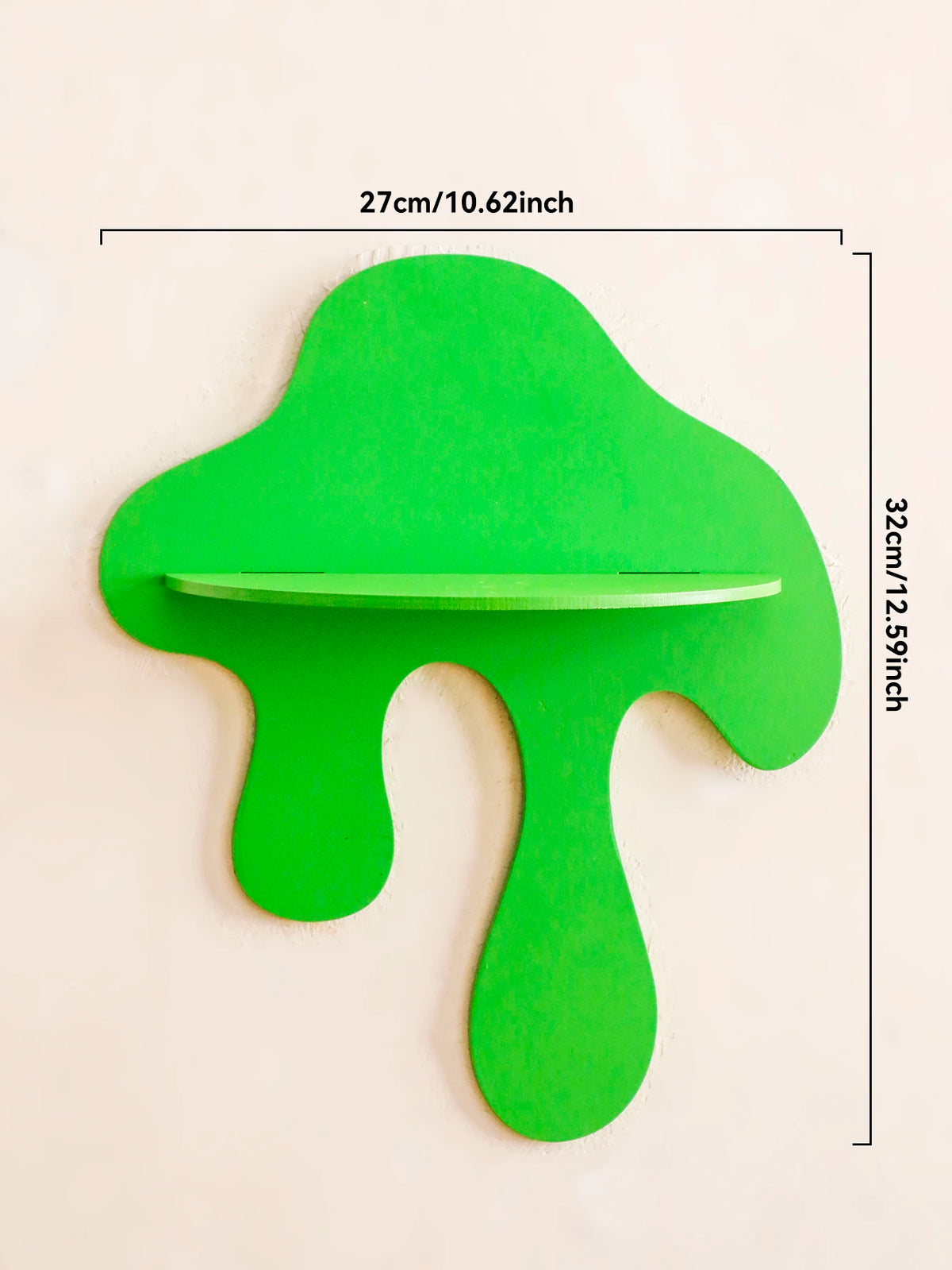 A bright green, cherry-shaped wooden wall shelf with a horizontal groove for display.
