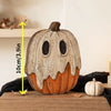 A distressed, orange and white vintage carved pumpkin decoration with a carved face sits on a wooden surface.