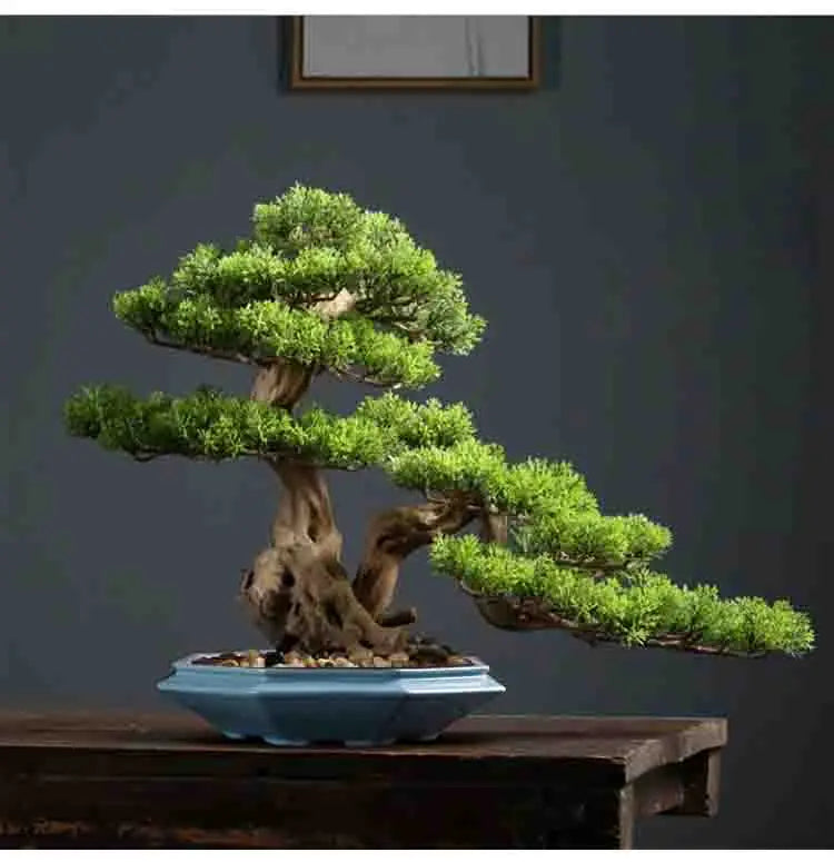 A miniature green bonsai tree planted in a blue ceramic flower pot on a wooden surface.