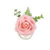 A pink silk rose corsage bracelet with green foliage and a pearl string.