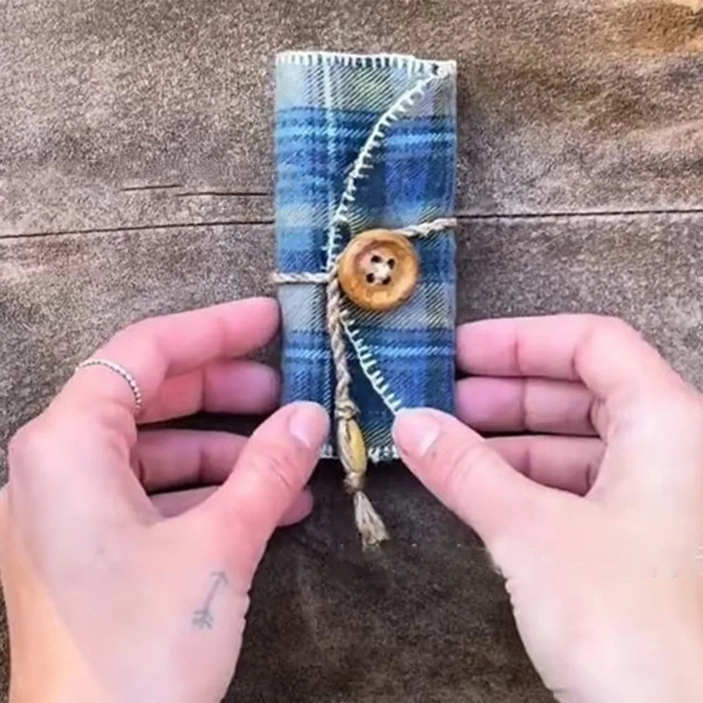 A handmade prayer quilt featuring a blue plaid fabric with a silver cross pocket shrine being held by hands.