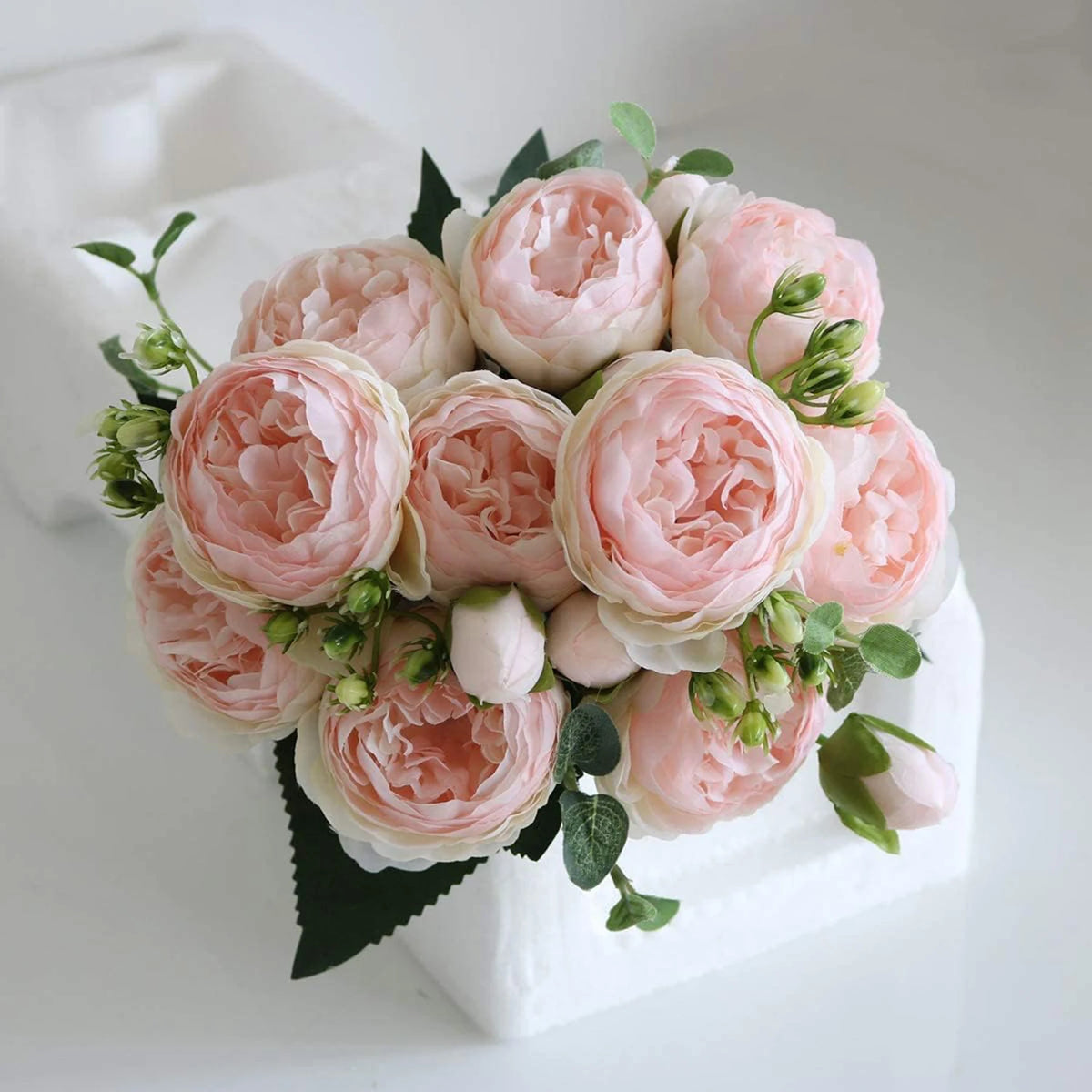 Ein Strauß aus rosa und weißen künstlichen Seerosen und Pfingstrosen in einer weißen Schale.
