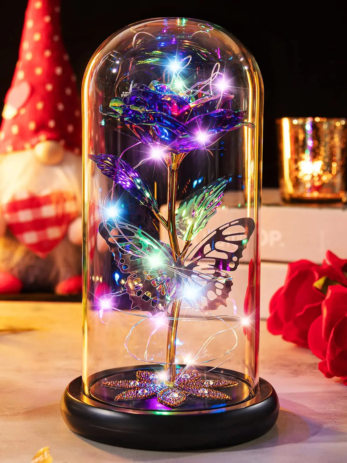 A glass dome features a crystal rose flower illuminated with sparkling light and butterfly wings.