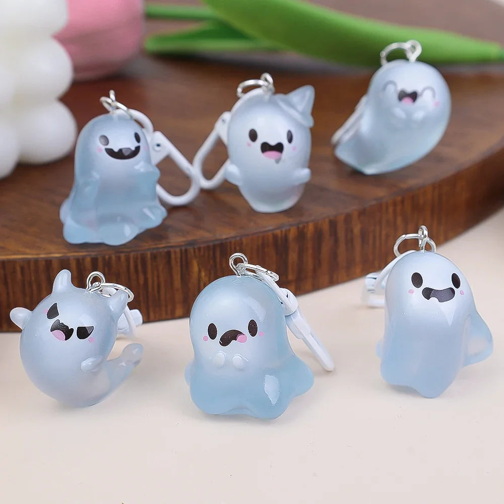 A set of light blue glow-in-the-dark ghost keychains shaped like cute, smiling ghosts.