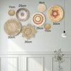 A collection of round boho straw wall hangings in various sizes and shades mounted on a white wall.