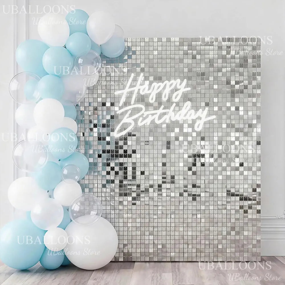 A display of light blue and white balloons against a silver sequin wall backdrop with happy birthday text.