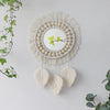 Miroir rond en macramé mural avec frange beige et accents de plumes suspendues.