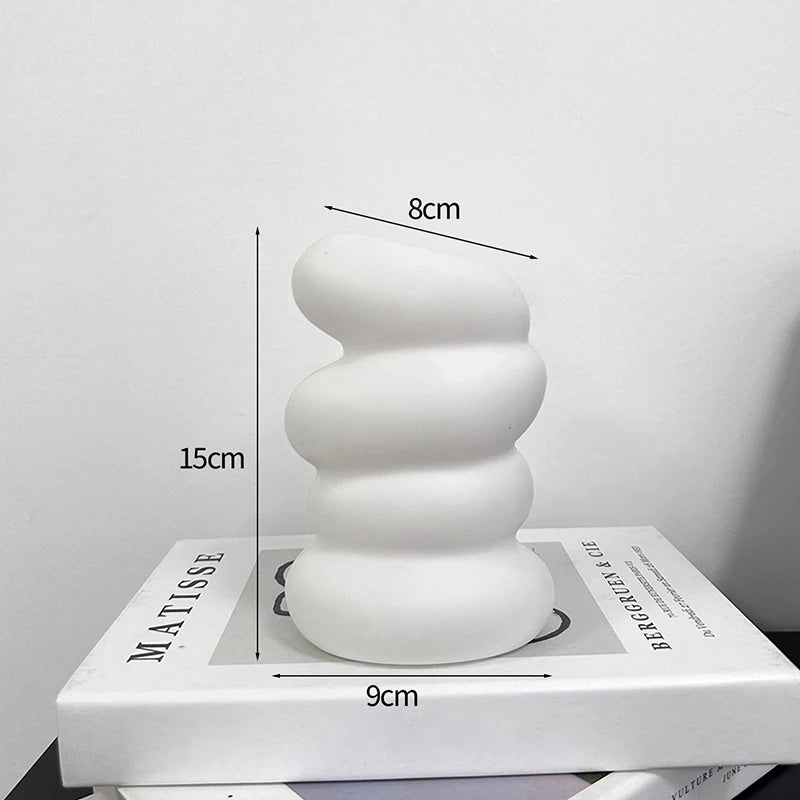 A smooth, white, stacked cylindrical decorative object with a textured surface.