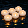 Several white floating LED candles are illuminated on dark water.