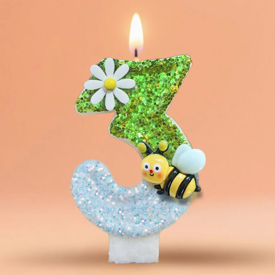 A birthday candle shaped like the number 3, decorated with a white flower and a bee, set against a soft orange background.