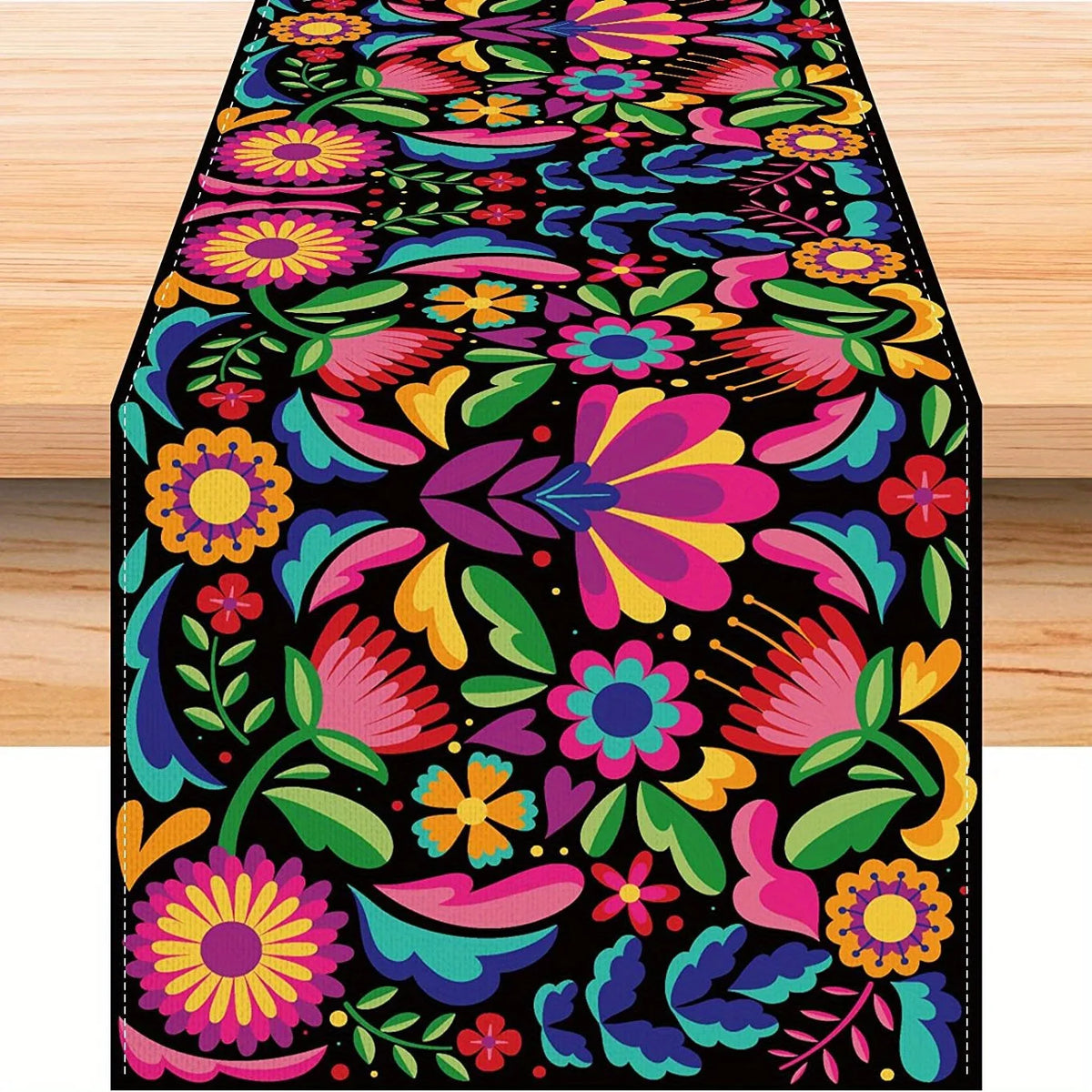 A vibrant floral pattern linen table runner featuring pink, purple, yellow, and teal flowers on a black background.