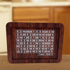 A dark wood savings box with a grid tracker showing various dollar amounts.