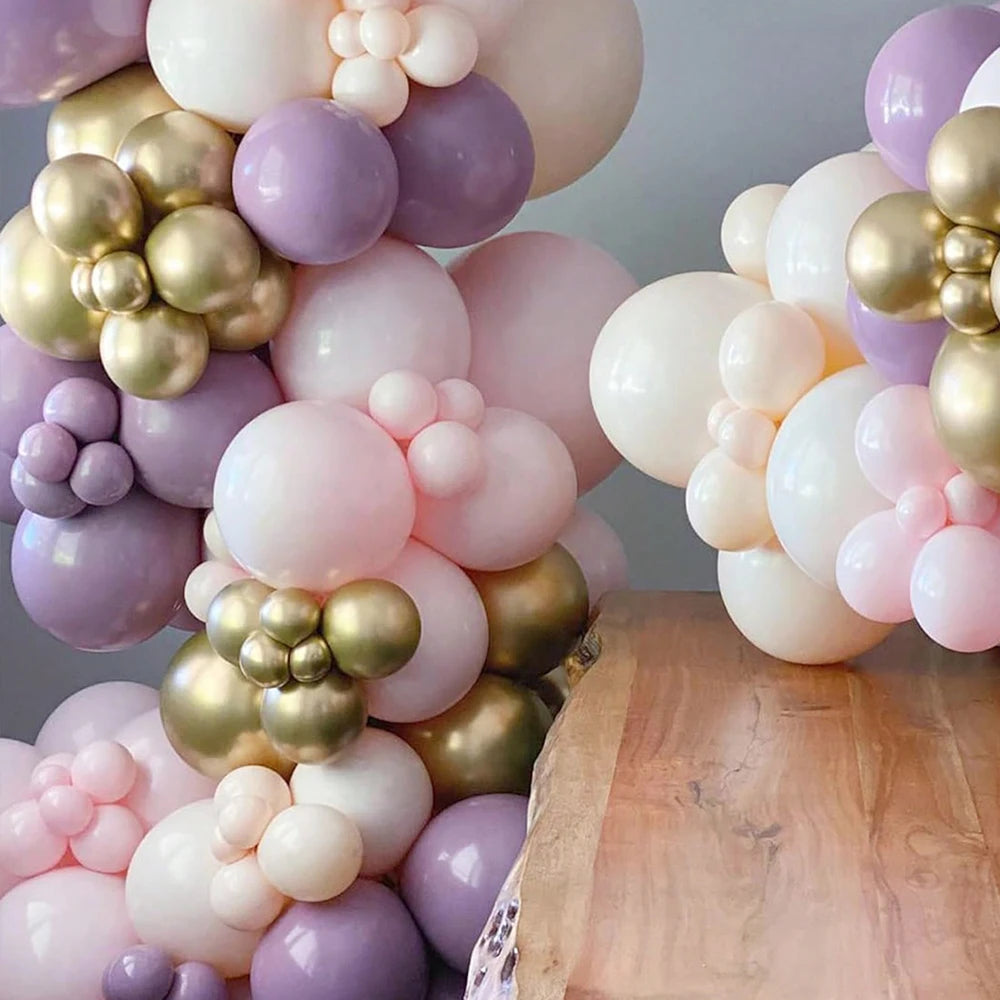 A close-up of a balloon garland arch featuring shades of purple, pink, and gold balloons.