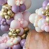 A close-up of a balloon garland arch featuring shades of purple, pink, and gold balloons.