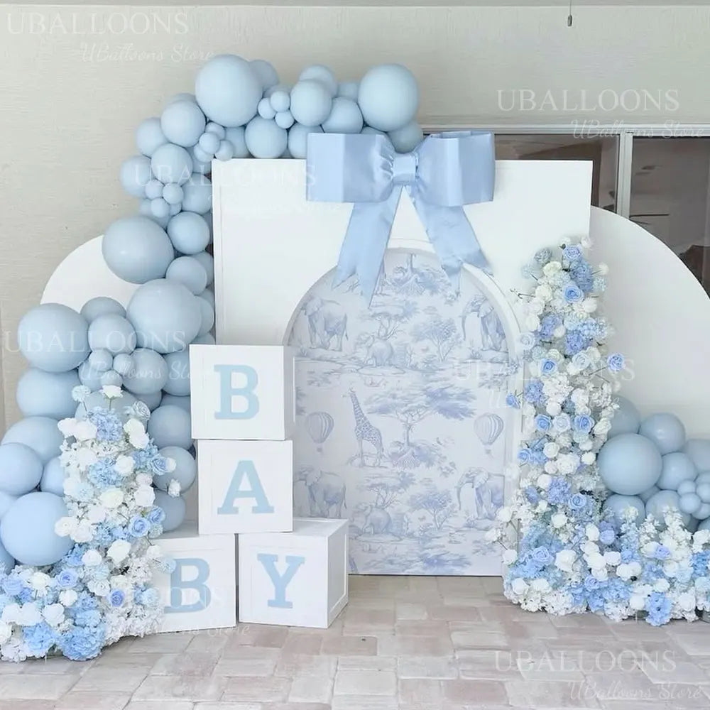 A pastel blue balloon arch kit decorated with white and light blue flowers for a baby shower or party backdrop.