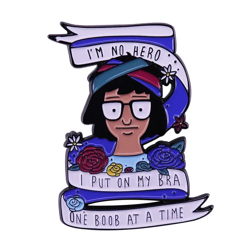 Enamel pin badge featuring a woman with dark hair wearing a blue bandana and text that reads I'm no hero I put on my bra one 
