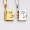 A gold-toned pendant necklace featuring an openable book charm with a handprint engraving and a silver-toned version.