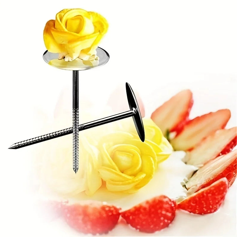 A gold-colored rose is placed on a cake with a metal piping tool and various strawberry slices.
