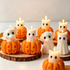 A collection of silicone candle molds featuring cute ghost, cat, dog, and pumpkin designs, lit by candles.