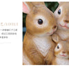 Two adorable hand-painted resin rabbit garden statues looking at the camera.