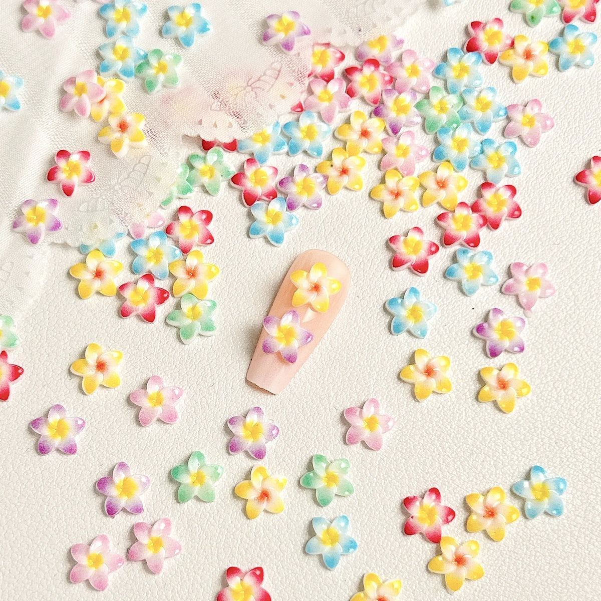 Una colección de 50 mini aderezos de uñas con forma de tortuga coloridos esparcidos sobre una superficie blanca.