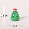 A small, green, three-tiered Christmas tree resin charm with a red Santa hat, shown against a white background.