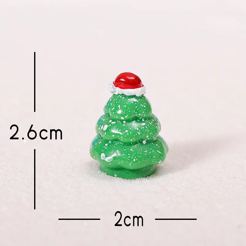 A small, green, three-tiered Christmas tree resin charm with a red Santa hat, shown against a white background.