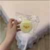 A hand holds a clear plastic bag containing a yellow, butter-textured squishy toy shaped like a banana bear.