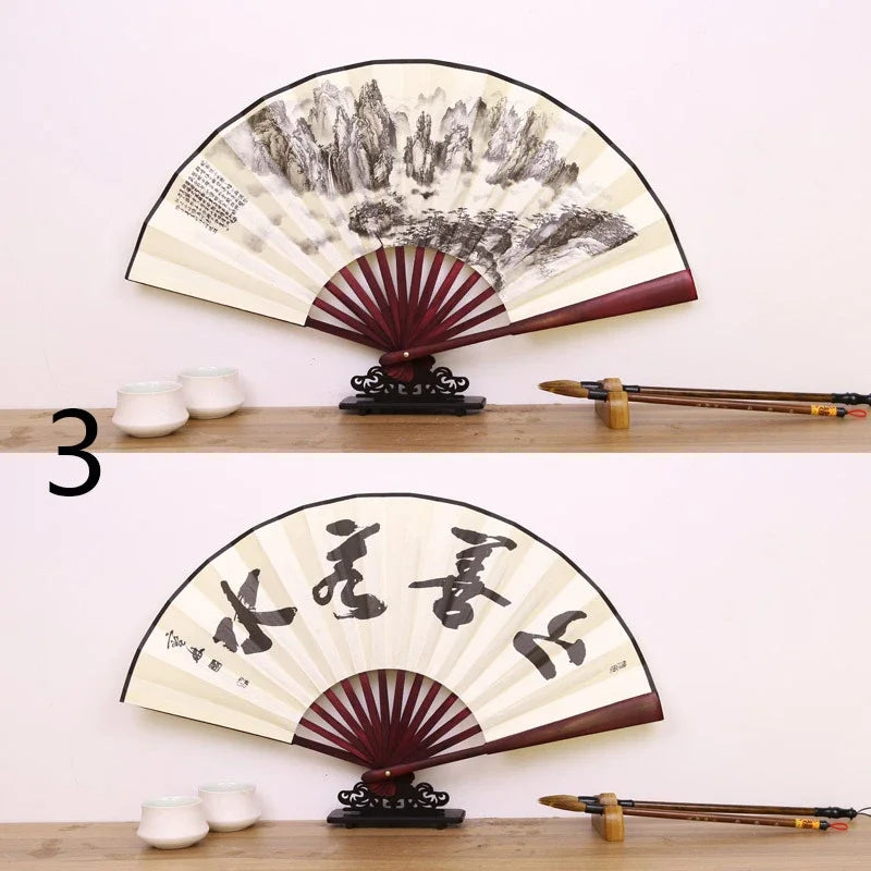 A black and white painted folding fan with a red border and Japanese calligraphy on a wooden display stand.