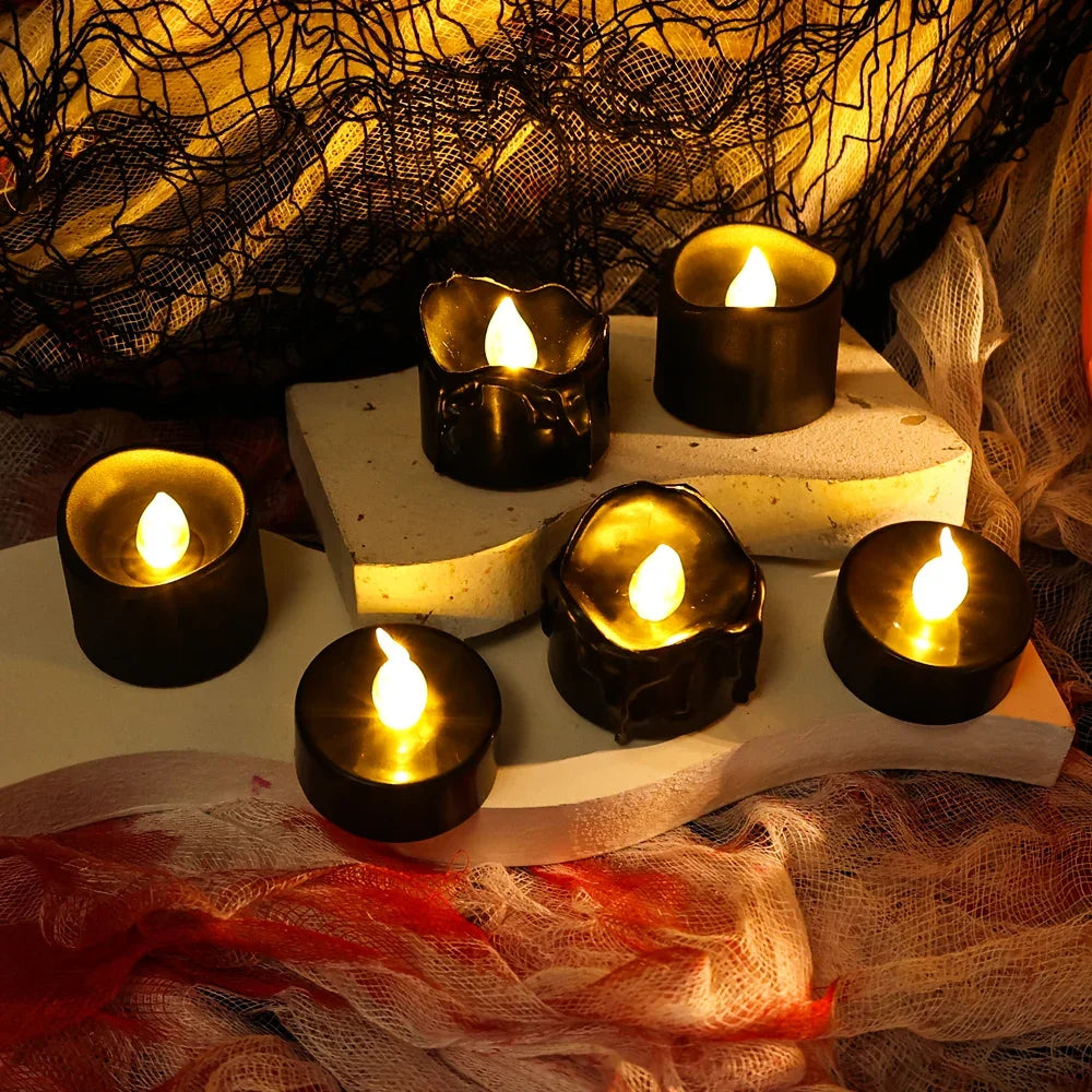 A collection of black LED candles with a warm white glow arranged on a light surface, set against a dark, textured background