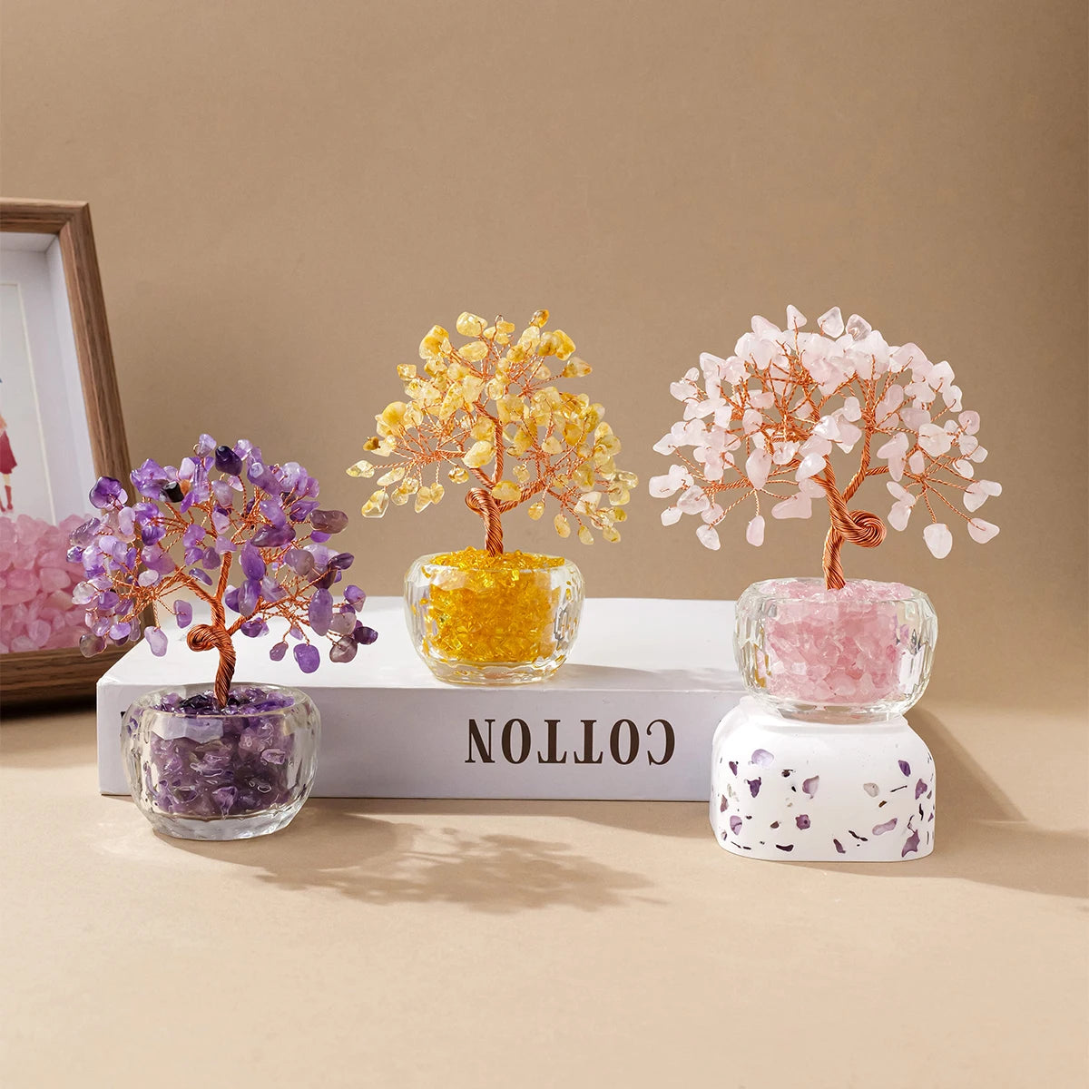 Three crystal money tree ornaments featuring yellow, pink, and purple quartz crystals in clear glass pots.