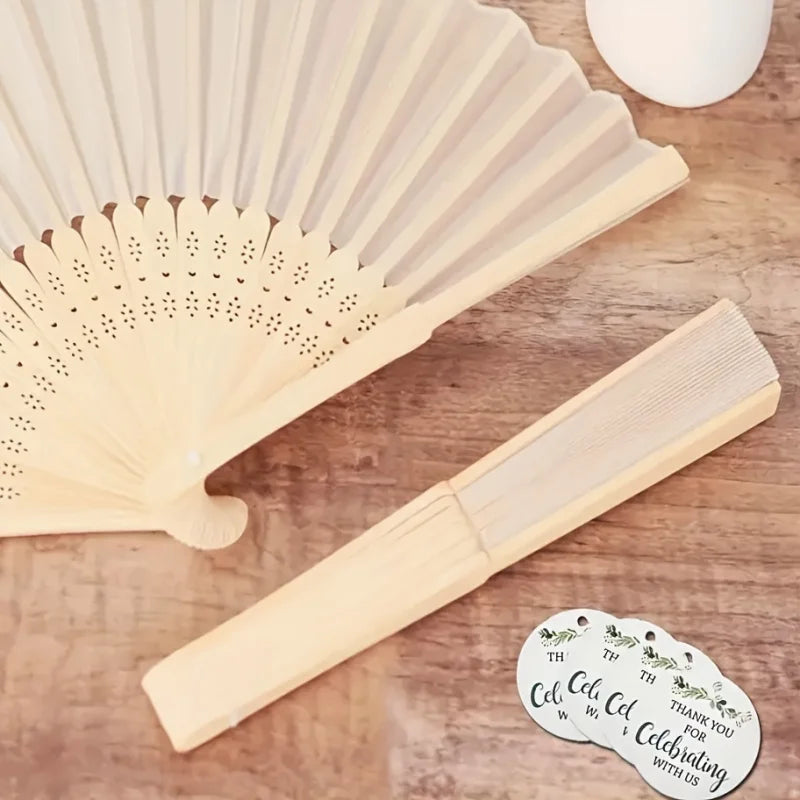 A light wood bridal handheld folding fan set with decorative elements is shown on a wooden surface.