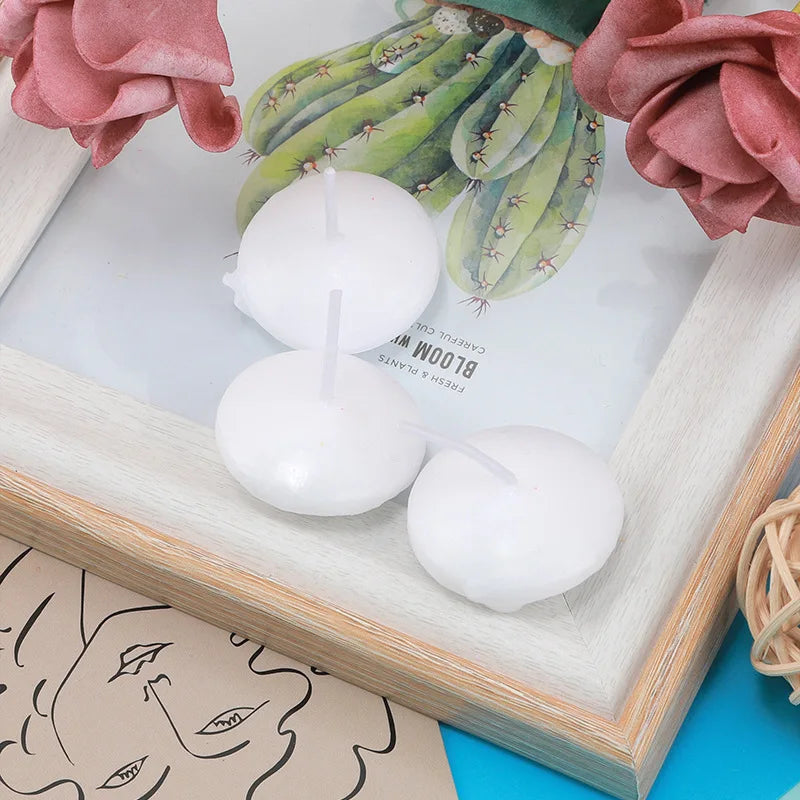 White floating candles surrounded by pink roses and green succulents in a wooden frame