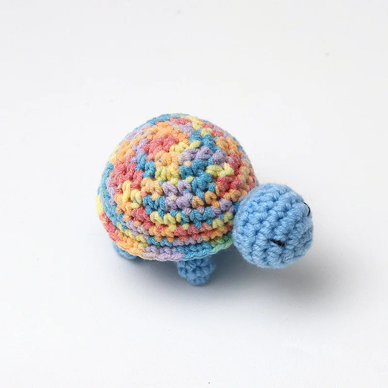Handmade crocheted turtle plush with multicolored shell and head, resting on a white background.