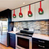 A set of four mini Christmas wreaths with ribbon bows and red berries displayed on kitchen cabinetry.