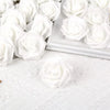 A close-up of white artificial foam rose decorations arranged in a white rectangular dish on a white textured surface.
